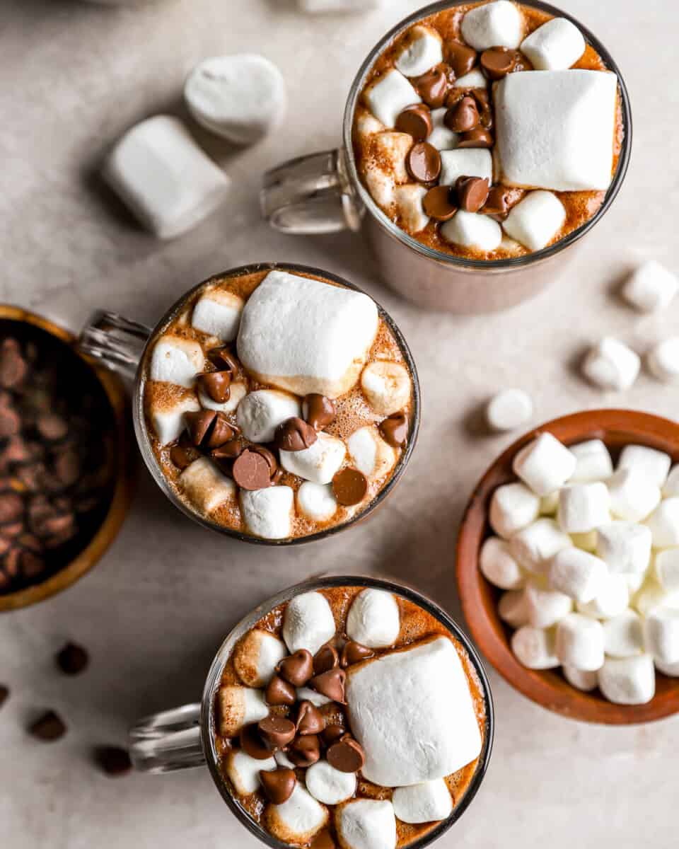Canecas de chocolate quente com marshmallows e gotas de chocolate.