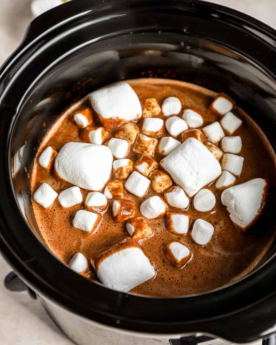 Uma panela elétrica recheada com chocolate quente e marshmallows.
