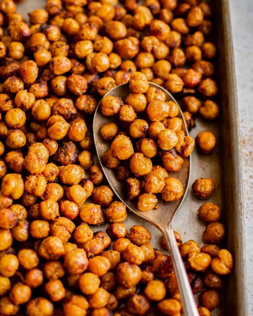roasted chickpeas on a baking sheet with a spoon.