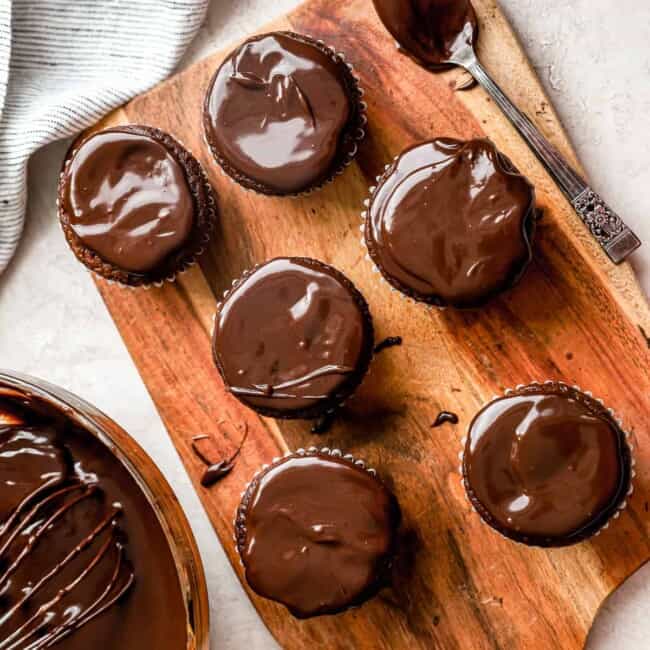 Cupcakes de chocolate com ganache de chocolate em uma tábua de madeira.