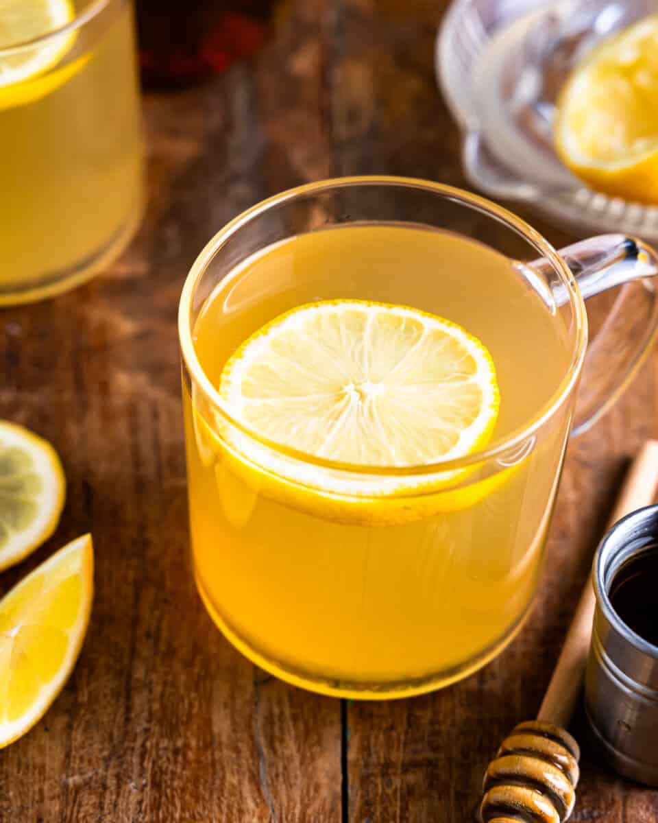 Uma xícara de chá com rodelas de limão e mel sobre uma mesa de madeira.