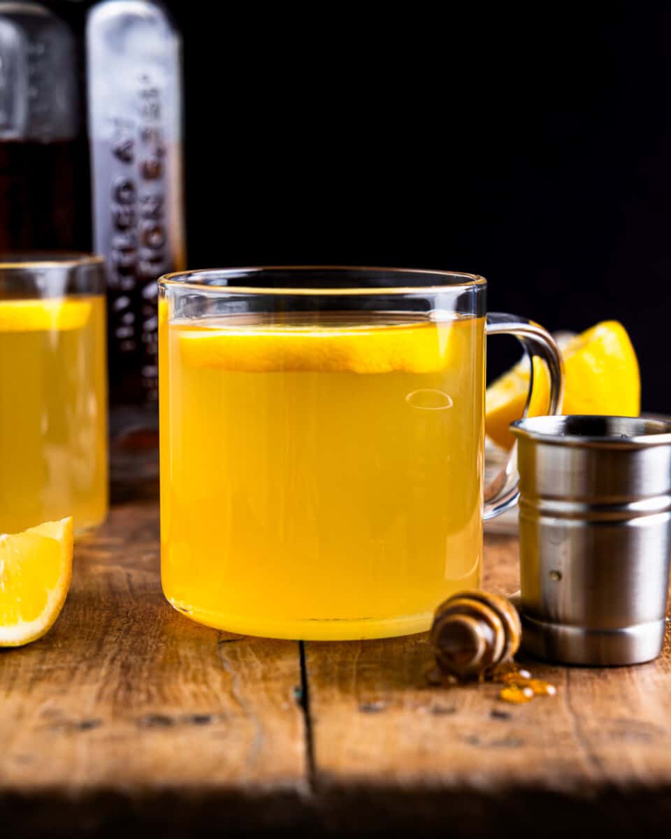 Uma xícara de limonada com mel e rodelas de limão sobre uma mesa de madeira.