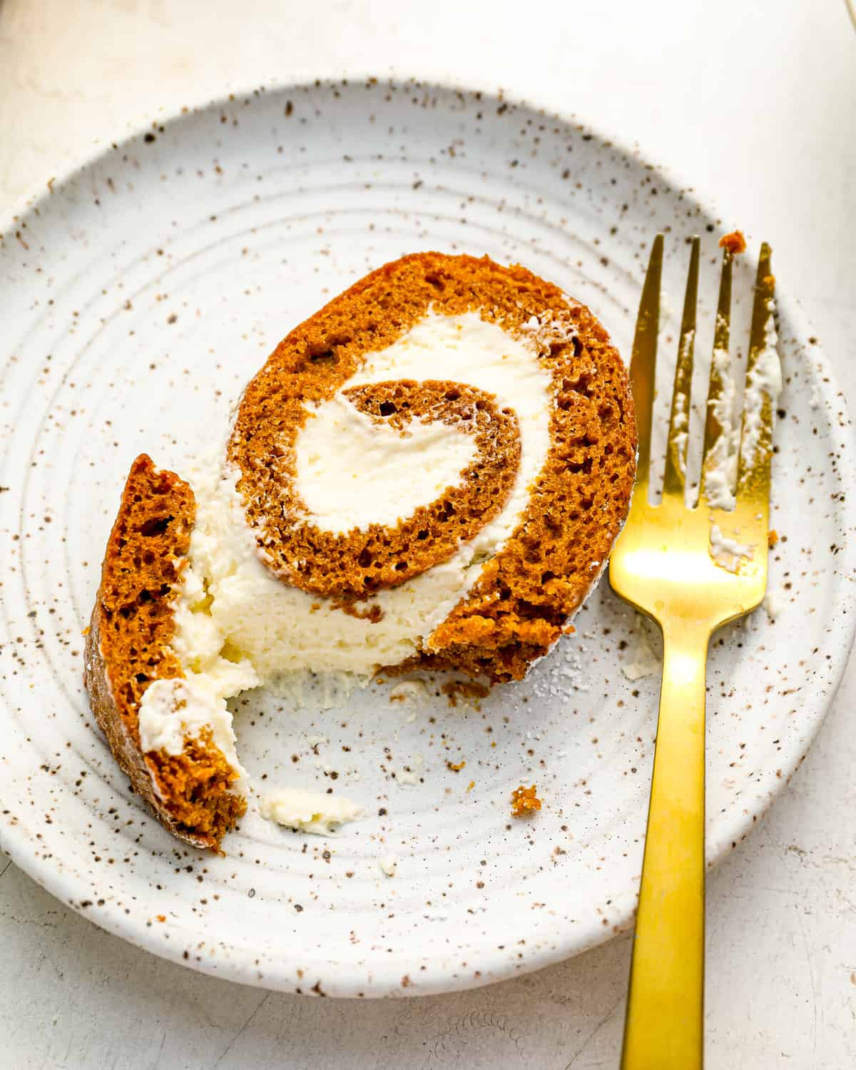 uma fatia de bolo de abóbora enrolada em um prato com um garfo.