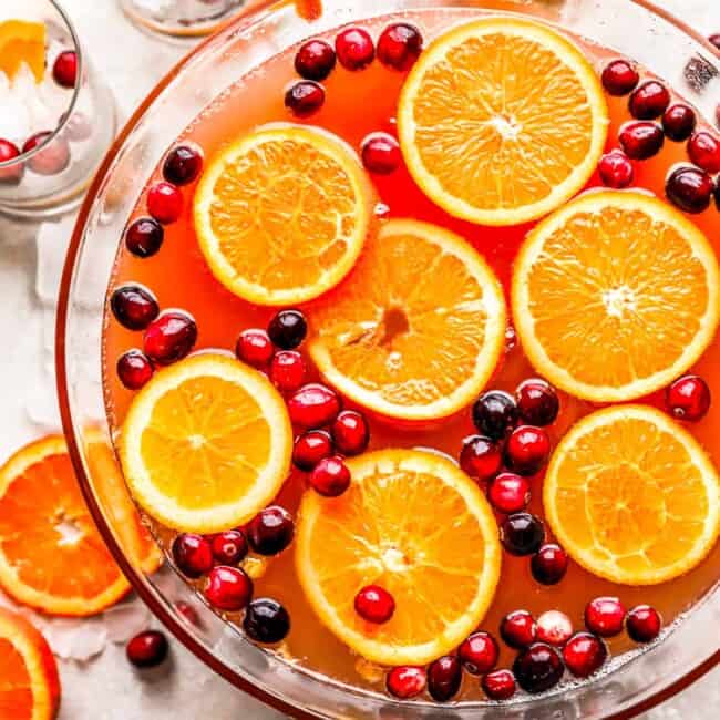 Uma tigela cheia de laranjas e cranberries.