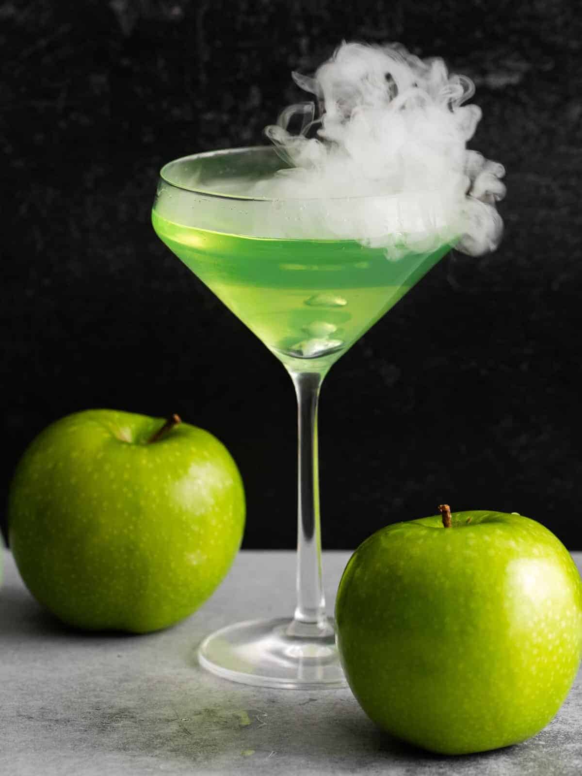 close-up de um martini de maçã verde venenosa com 2 maçãs verdes.