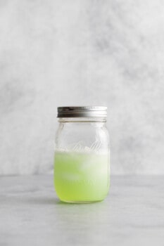 martini de maçã venenosa batido em um frasco de vidro selado com gelo.