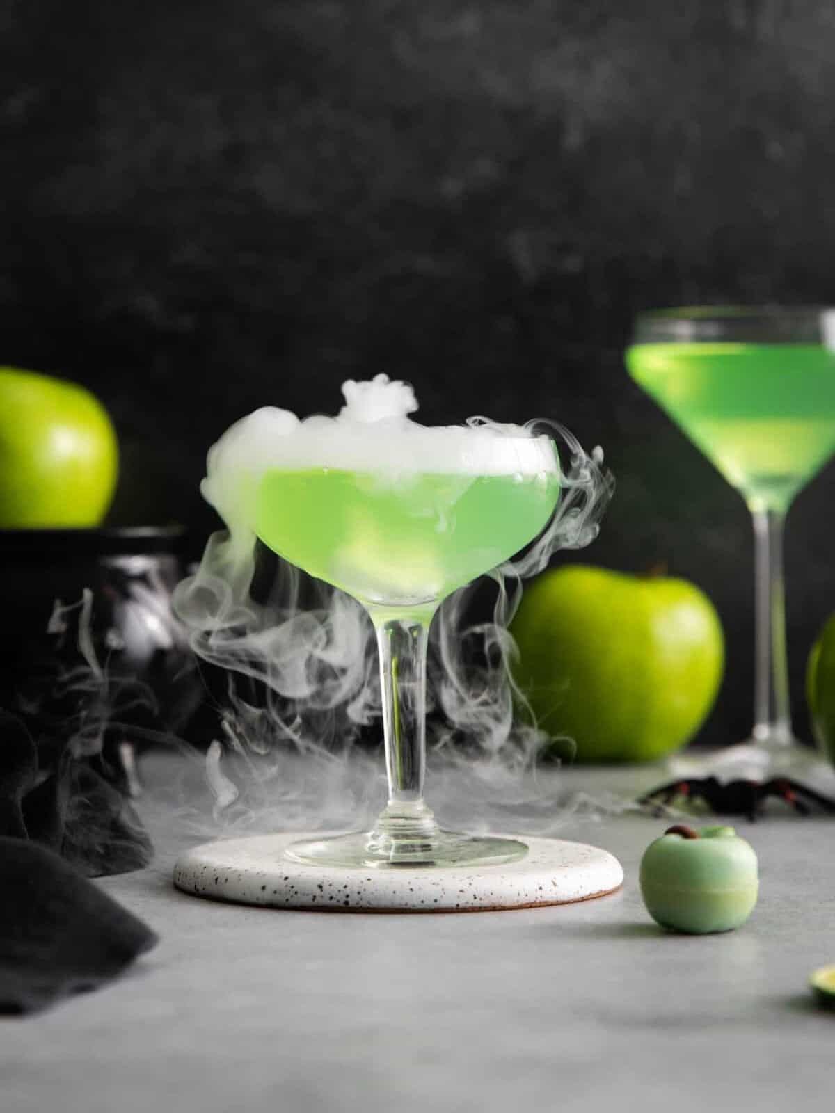 um martini de maçã venenoso fumegante em uma base para copos branca.