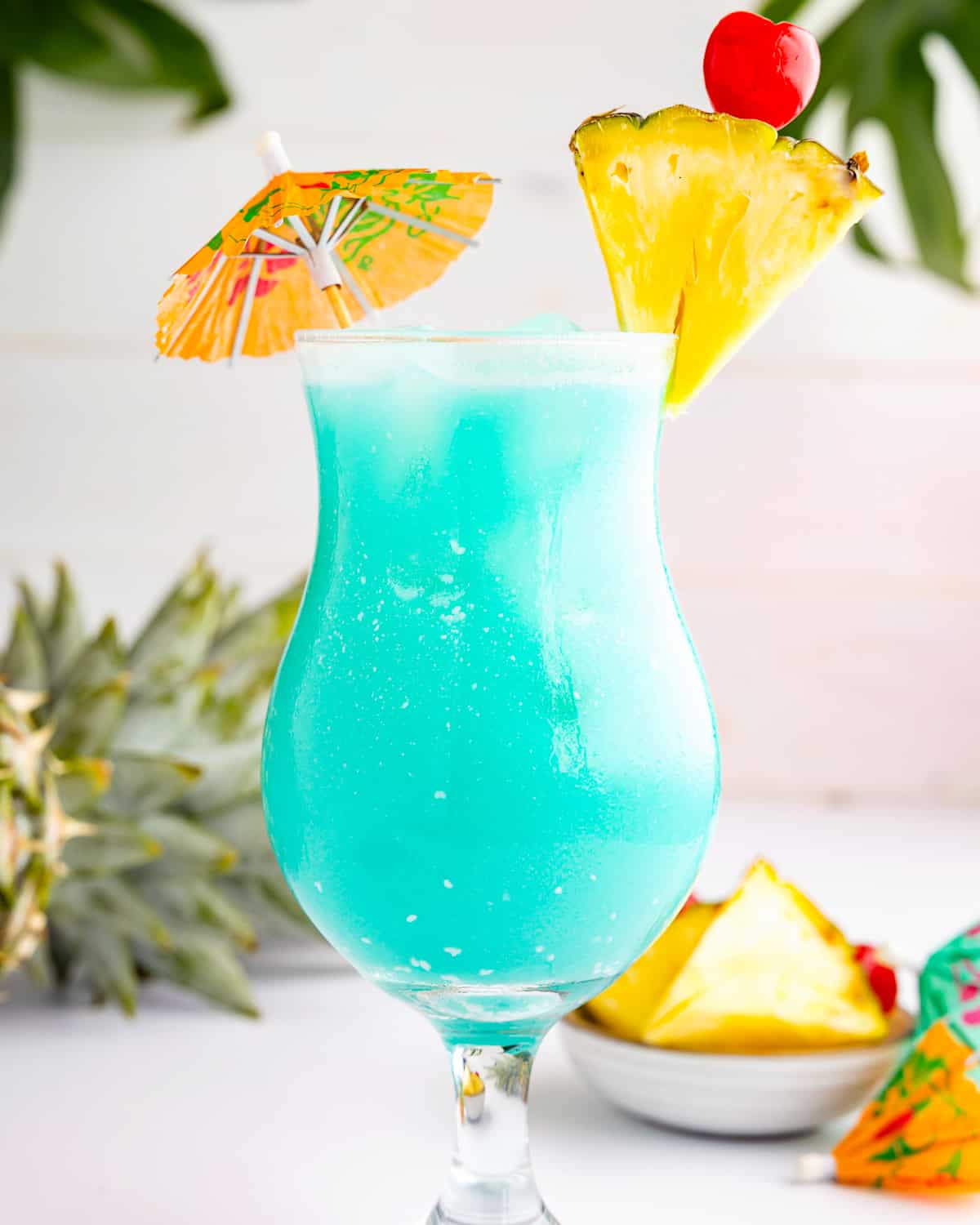 um coquetel havaiano azul com enfeites de abacaxi em um copo.