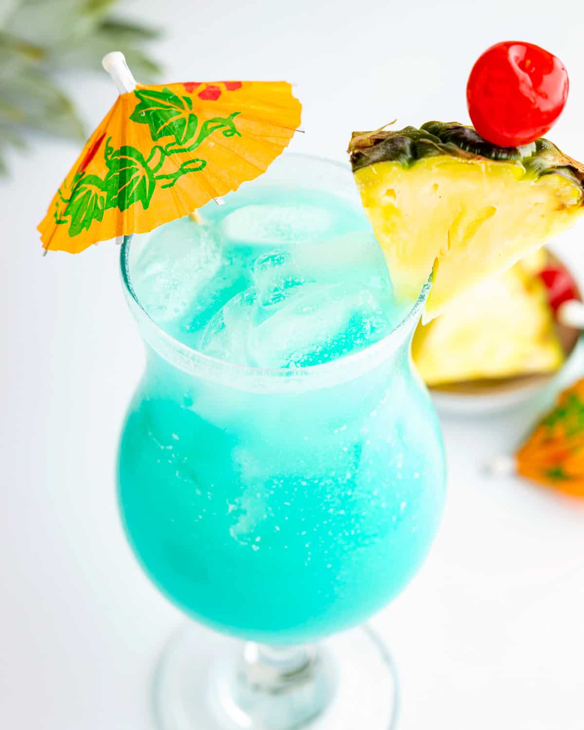 uma bebida havaiana azul com abacaxi e guarda-chuva.