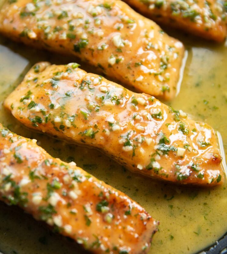 close-up de filés de salmão com manteiga de alho na frigideira
