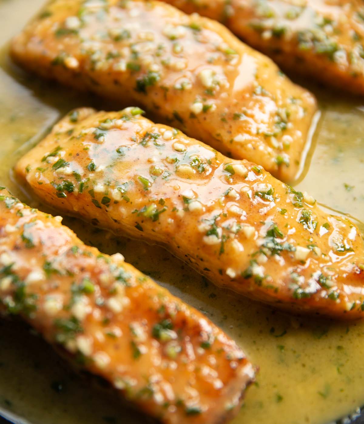 close up shot of garlic butter salmon fillets in pan