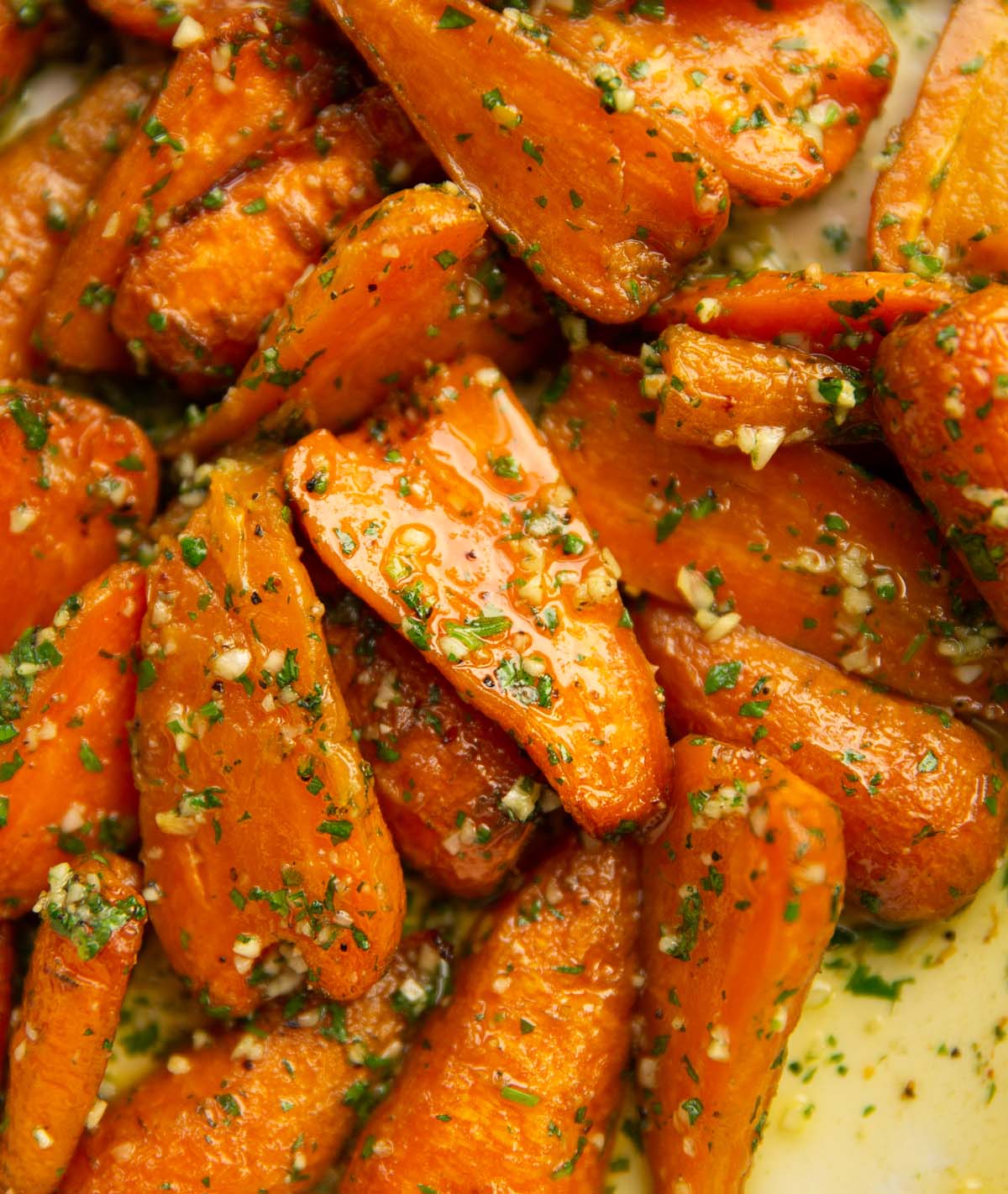 close up shot of garlic roasted carrots in large white baking dish