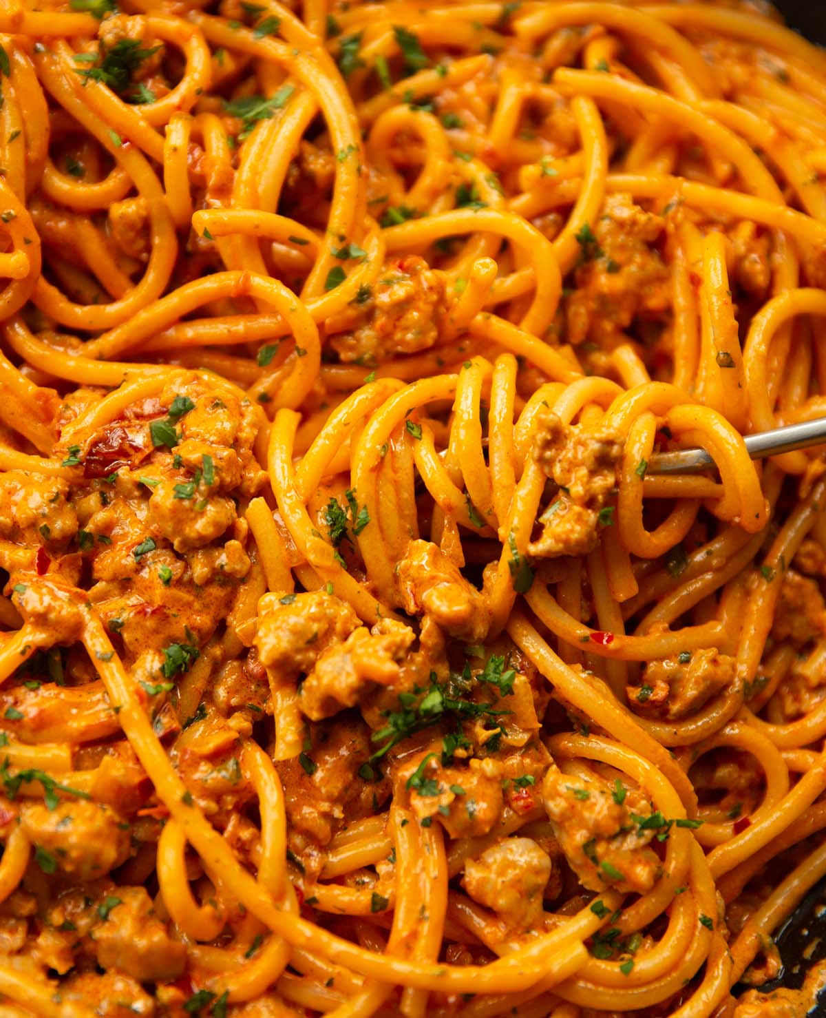close up shot of fork twirling into pan of sausage harissa pasta