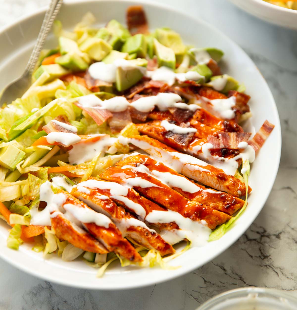 buffalo chicken salad served with ranch in large white shallow dish