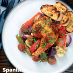 Bandeja espanhola de frango e chouriço assada com legumes, servida com pão torrado com sobreposição de título.