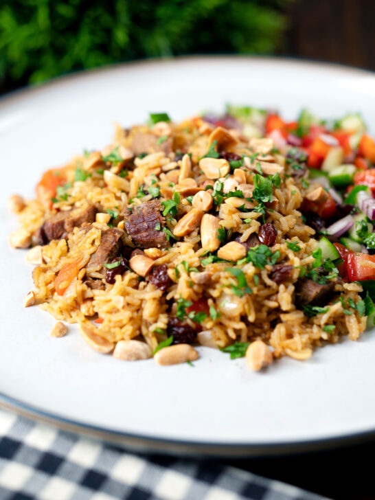Kabsa de cordeiro, arroz da Arábia Saudita com amêndoas e passas servido com salada picada.