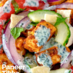 Close-up de salada paneer tikka com molho de iogurte raita com uma sobreposição de título.