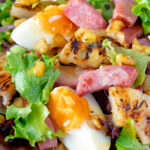 Close-up de salada de presunto com abacaxi grelhado, ovos cozidos e batatas com sobreposição de título.