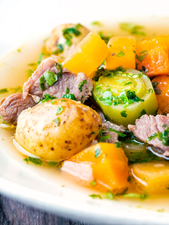 Feche o cawl galês, uma sopa à base de caldo de cordeiro e vegetais em uma tigela branca.