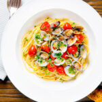 Espaguete alle vongole ou macarrão de mariscos com tomate, salsa e alho com uma sobreposição de título.