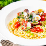 Spaghetti alle vongole ou macarrão de mariscos com tomate, salsa e alho com sobreposição de título.