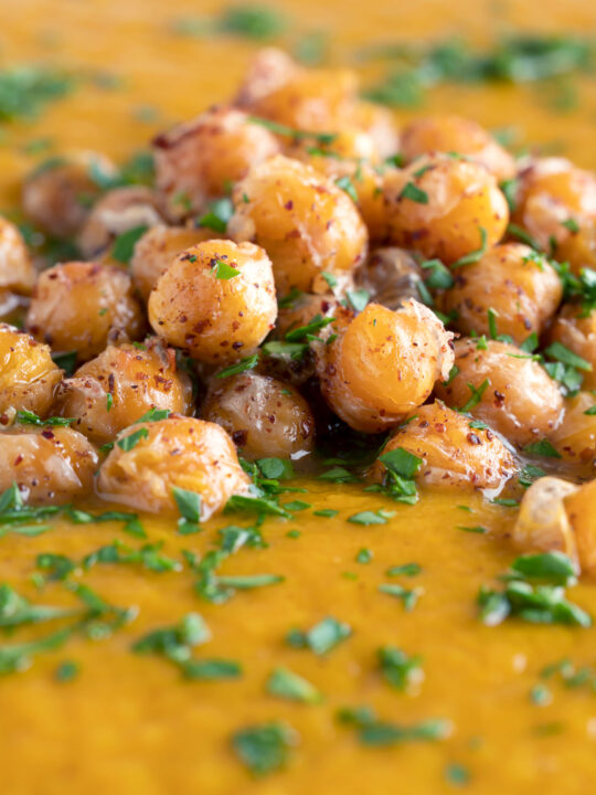 Feche a sopa picante de cenoura assada com croutons crocantes de grão de bico.